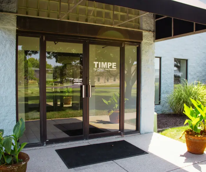 Glass double door entrance to the Timpe office building featuring the white Timpe logo on the door.